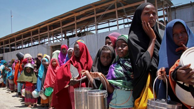 FILE - In this photo taken Feb. 25, 2017, displaced Somali girls who fled the drought in southern Somalia stand in a queue to receive food handouts at a feeding center in a camp in Mogadishu, Somalia.